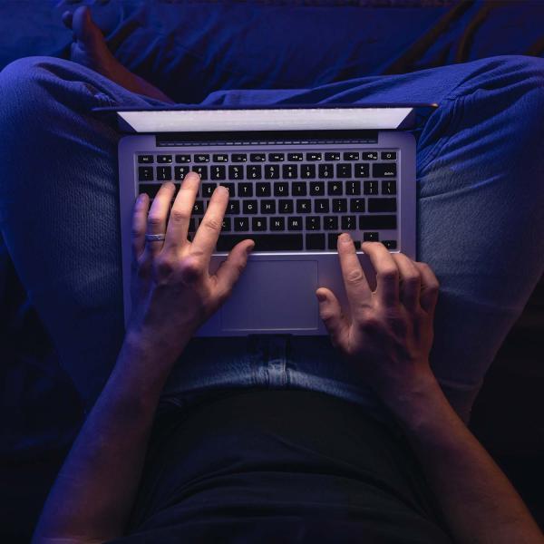 Close up of hands on a laptop keyboard at night